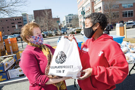 GBFB Client Maria receiving a bag of fresh food at a distribution site.