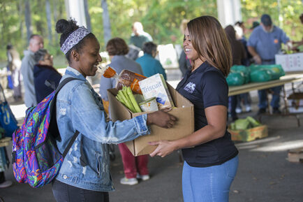 College student being handed a box of fresh food