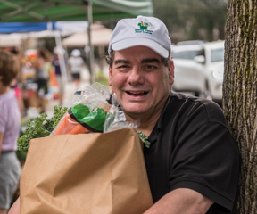 Smiling man holding full grocery bag