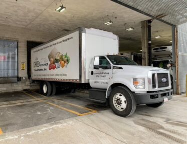 The Loaves and Fishes white truck is parked outside of the GBFB warehouse to pick up produce and food.