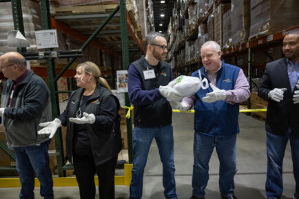 A group of volunteers stands in a line to pass a turkey.