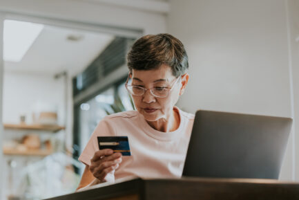 Thai senior adult woman reading an information on credit to installing on online shopping.