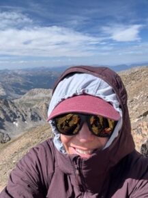 Photo of Diane Bevan from the top the summit of a mountain.